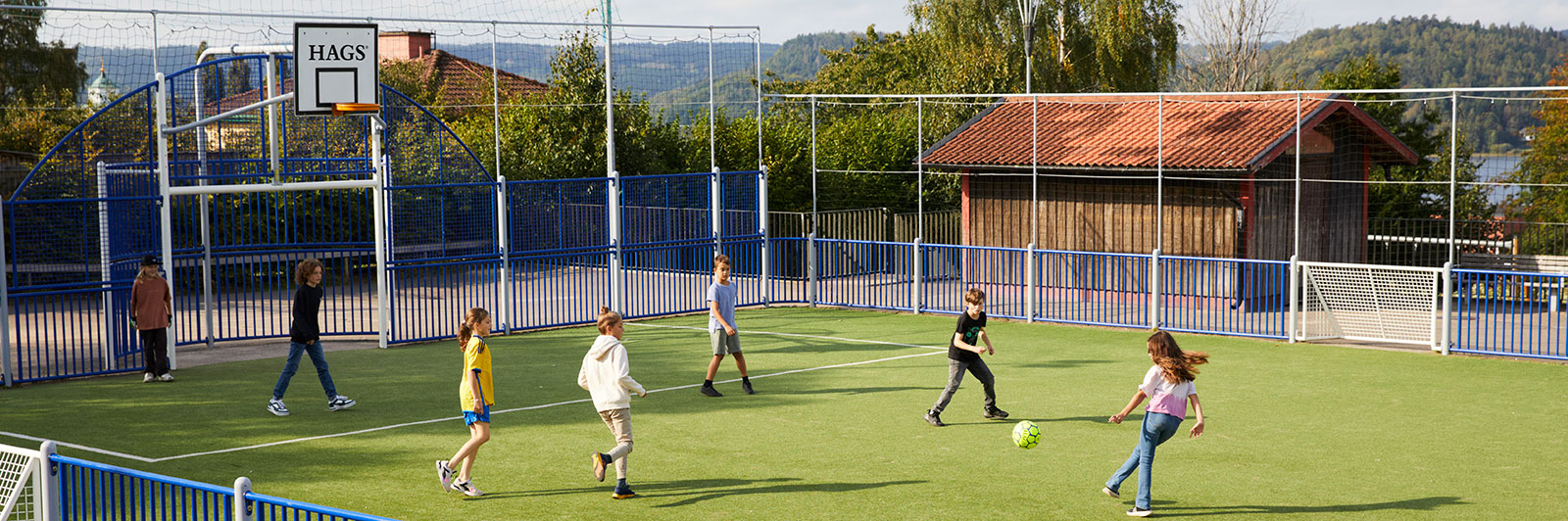 Children play football at a public sports court.